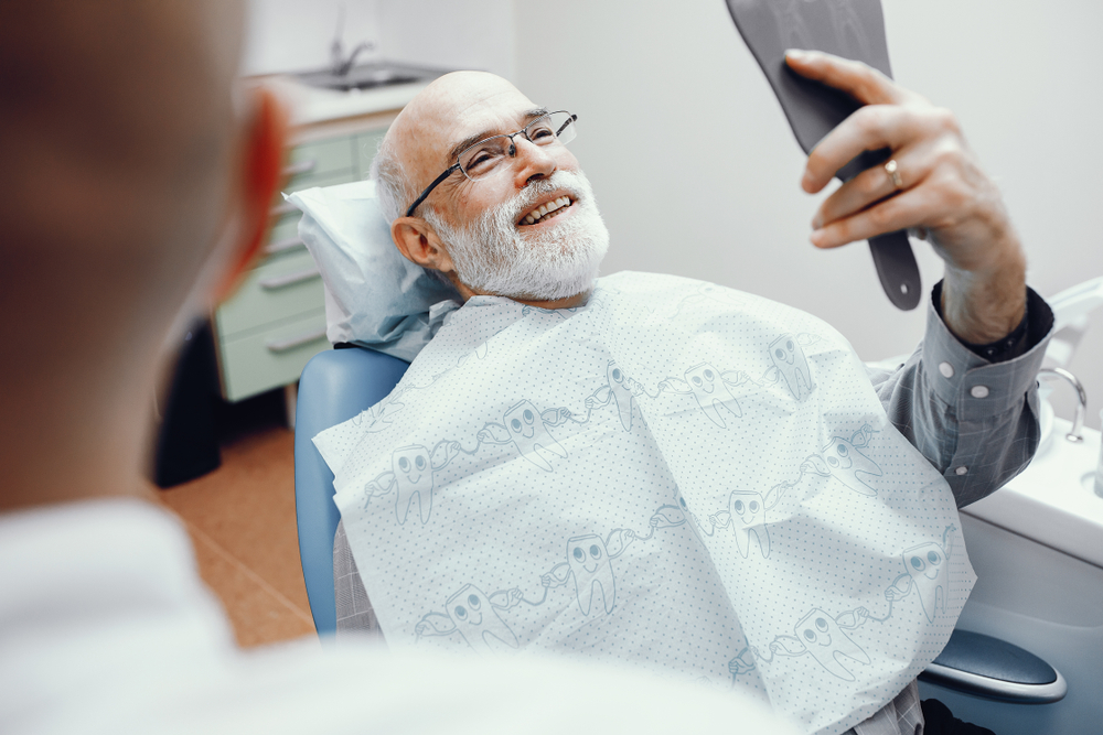 older man looking at his smile at the dentist