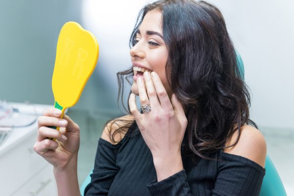 woman looking at her smile at the dentist - general dentistry services
